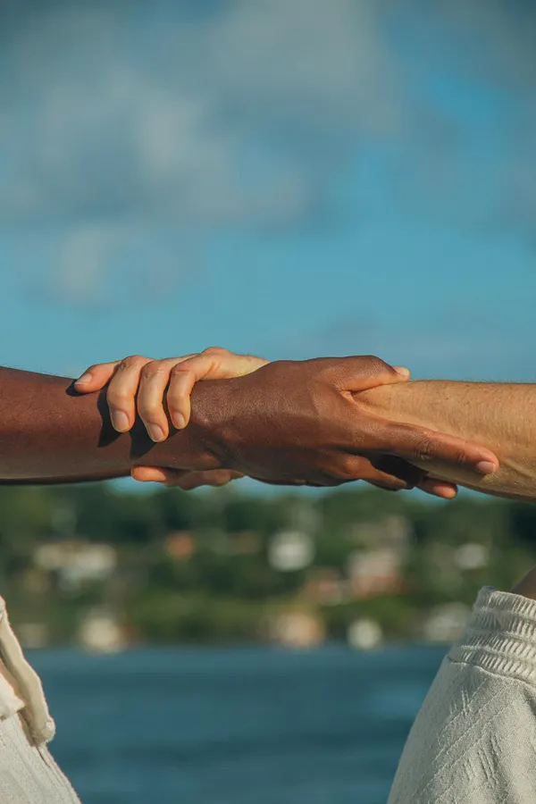 Mains entrelacees devant la mer - Brasil Sunshine, lien entre cultures
